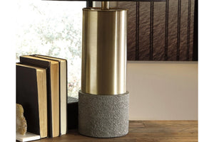 Lámpara decorativa con base metálica y fondo gris texturizado sobre superficie de madera.