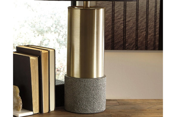 Lámpara decorativa con base metálica y fondo gris texturizado sobre superficie de madera.