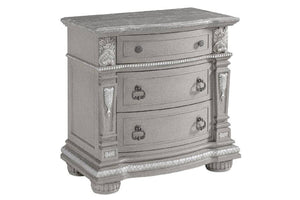 Mesa de noche gris con tres gavetas sobre un fondo blanco. 