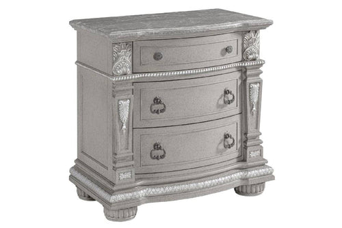 Mesa de noche gris con tres gavetas sobre un fondo blanco. 