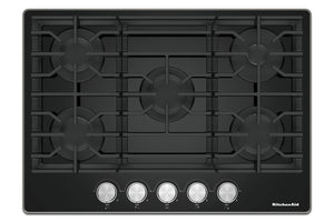 Un tope de cocción de gas KitchenAid negra con cinco perillas de control plateadas a lo largo del borde inferior, mostrada desde una perspectiva superior sobre un fondo blanco.