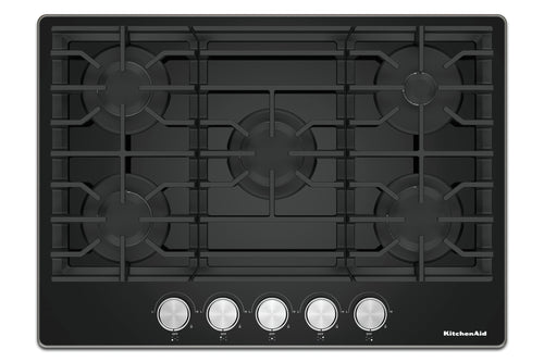 Un tope de cocción de gas KitchenAid negra con cinco perillas de control plateadas a lo largo del borde inferior, mostrada desde una perspectiva superior sobre un fondo blanco.