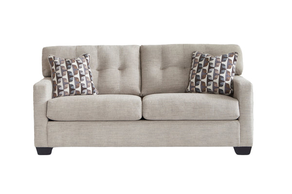 Sofá de color beige con cojines decorativos con patas acabadas sobre un fondo blanco. 