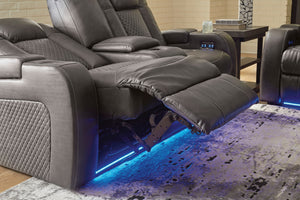 Loveseat reclinables grises con iluminación LED sobre un suelo alfombrado.