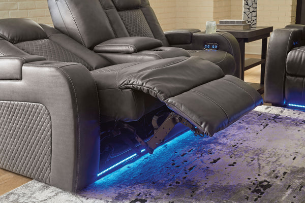 Loveseat reclinables grises con iluminación LED sobre un suelo alfombrado.