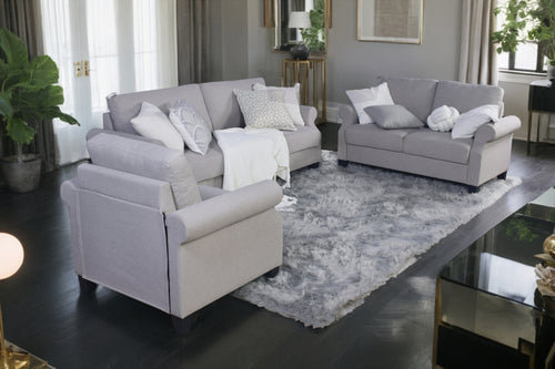 Conjunto de sofá, loveseat y butaca gris claro con cojines blancos decorativos en una sala moderna. 