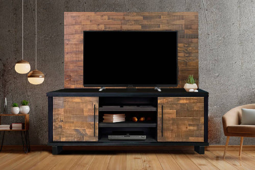 Televisor sobre una consola de entretenimiento de madera en una habitación con pared gris y piso de madera.