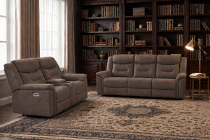 Un sofá y loveseat reclinable tapizado marrón, situados en una sala de estar decorada con buen gusto que cuenta con estanterías de madera oscura, una alfombra estampada, cortinas y una lámpara de pie.