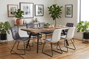 Juego de comedor con mesa y seis sillas de tela con patas de metal, plantas y cuadros enmarcados en una pared gris claro.