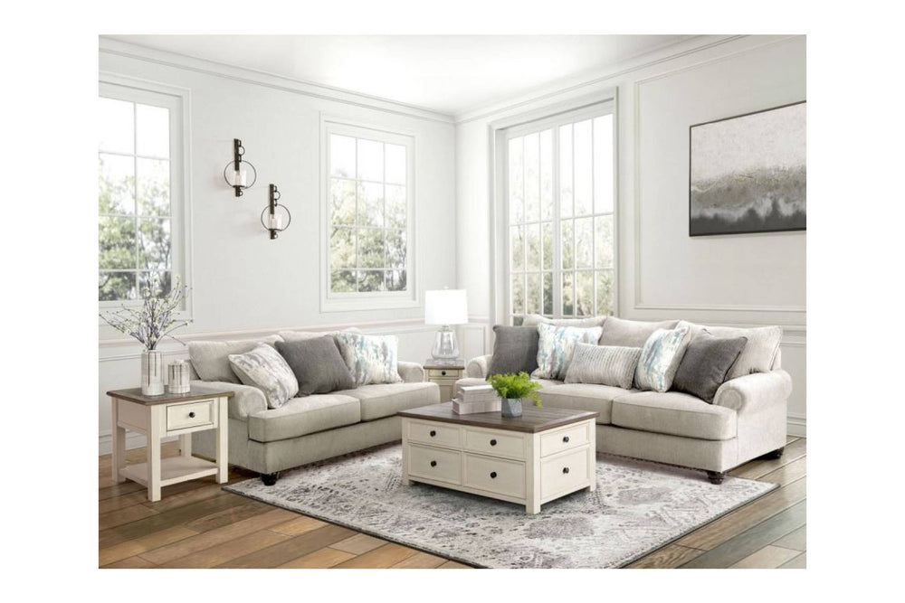 Sofá y loveseat de color beige con cojines sobre un fondo blanco. 