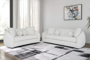 Sofá y loveseat de color blanco con cojines en una sala moderna. 