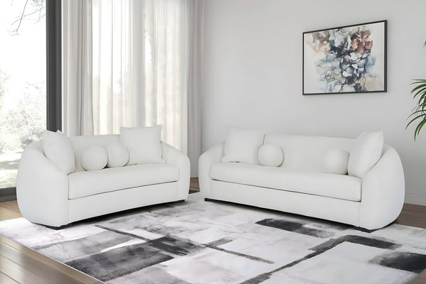 Sofá y loveseat de color blanco con cojines en una sala moderna. 