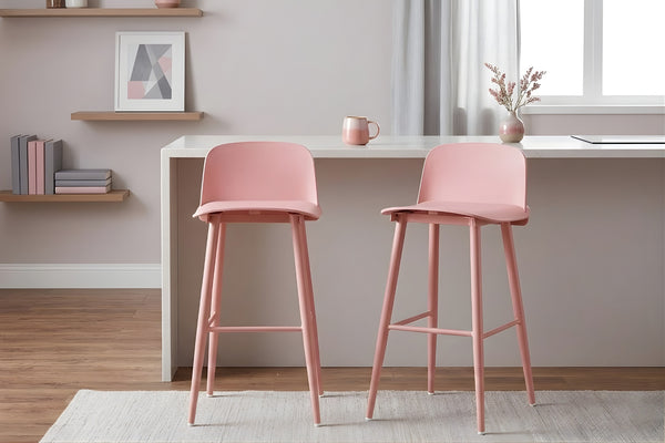 Dos taburetes rosas en una habitación con una encimera de cocina detrás y elementos decorativos.