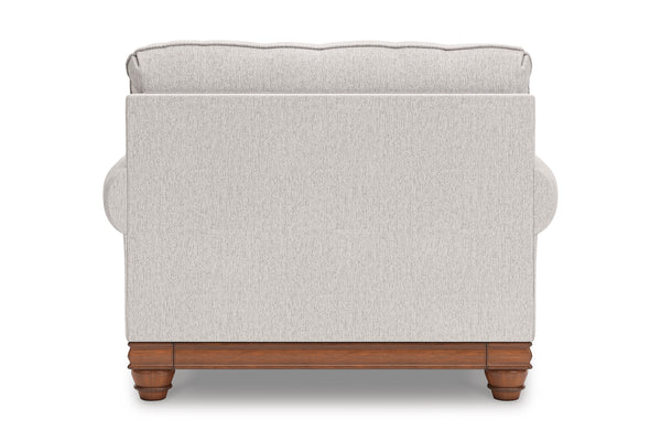 Vista posterior de silla de acento de color beige con brazos y un cojín decorativo sobre un fondo blanco. 