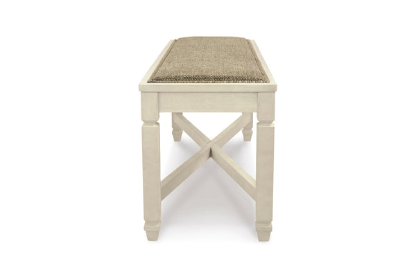 Un banco de madera blanca con un cojín de asiento tejido de color beige, mostrado desde un ángulo frontal de tres cuartos sobre un fondo blanco.