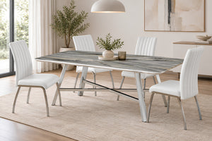 Juego de comedor moderno con mesa rectangular con acabado aspecto mármol gris y base cromada en X, acompañada de seis sillas tapizadas en blanco con patas cromadas, sobre una alfombra texturizada en tono beige.