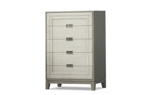 Cómoda alta de cinco gavetas con acabado gris claro y textura tipo madera. Cuenta con paneles enmarcados, tiradores metálicos rectangulares y patas cónicas, ofreciendo un diseño contemporáneo y elegante para dormitorio.
