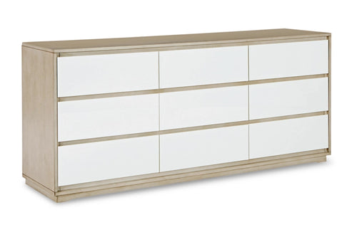 Un gavetero moderno de seis gavetas con puertas blancas de acabado alto brillo y un marco de madera natural clara, mostrado desde un ángulo de tres cuartos sobre un fondo blanco.