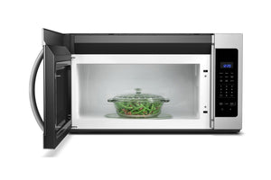 Microondas con extractor con un plato de judías verdes en su interior sobre un fondo blanco.