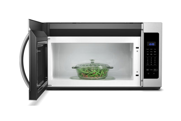 Microondas con extractor con un plato de judías verdes en su interior sobre un fondo blanco.