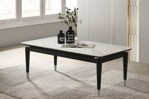 Mesa de centro rectangular con patrón de mármol blanco con objetos decorativos en un ambiente de sala. 