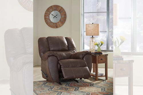 Butaca reclinable de color marrón oscuro en una sala con objetos decorativos. 