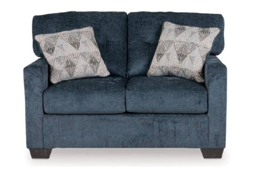 Loveseat azul oscuro con dos cojines decorativos sobre un fondo blanco. 