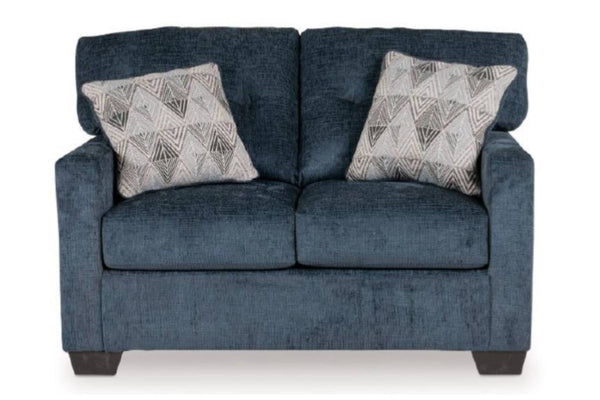Loveseat azul oscuro con dos cojines decorativos sobre un fondo blanco. 