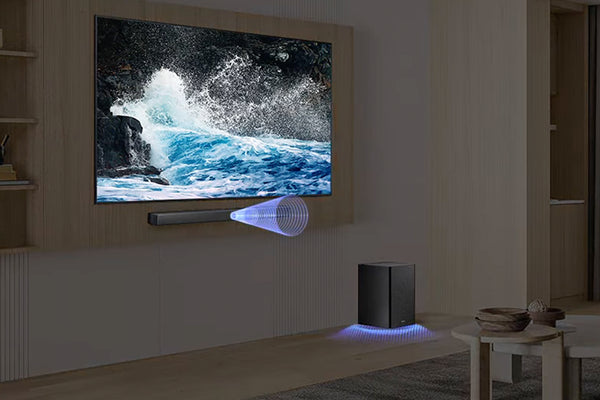 Moderna sala de estar con un televisor grande que muestra una escena de la naturaleza, un altavoz y una mesa pequeña.