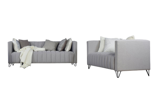Sofá y loveseat de color gris claro con cojines decorativos sobre un fondo blanco. 