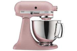 Una batidora de pie KitchenAid Artisan de color rosa con tazón y asa de acero inoxidable, mostrada sobre un fondo blanco liso.