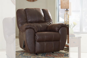 Butaca reclinable de color marrón oscuro en una sala con objetos decorativos. 