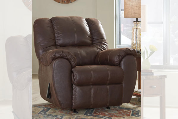 Butaca reclinable de color marrón oscuro en una sala con objetos decorativos. 