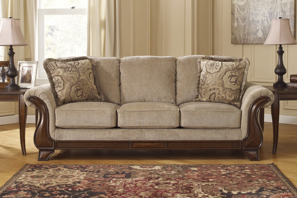 Sofá beige con cojines decorativos sobre fondo blanco.