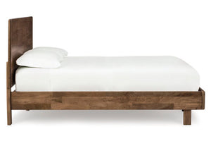 Vista lateral de cama hecha de madera marrón con acolchado blanco sobre un fondo blanco. 