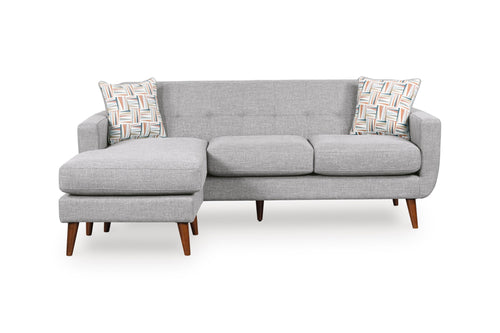 Sofa chaise de color gris claro con patas acabadas en madera y con dos cojines decorativos sobre un fondo blanco. 