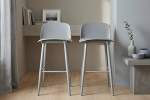 Dos taburetes grises en una habitación con un escritorio y objetos decorativos.