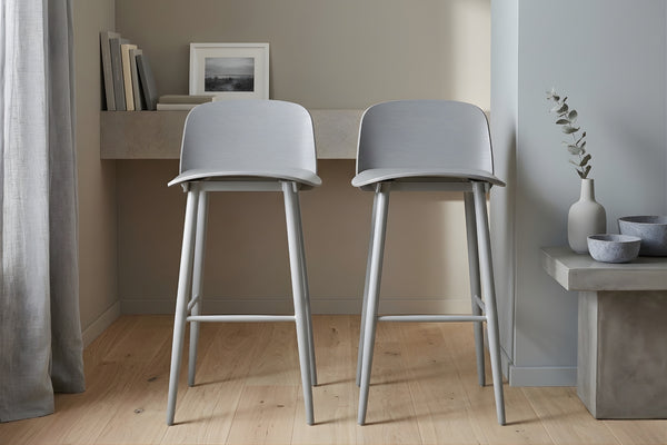 Dos taburetes grises en una habitación con un escritorio y objetos decorativos.