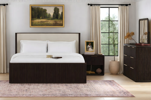 Habitación moderna con una cama, un gavetero con espejo y una mesa de noche. 