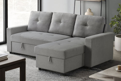 Sofá chaise con almacenamiento de color gris en una sala minimalista con objetos decorativos. 