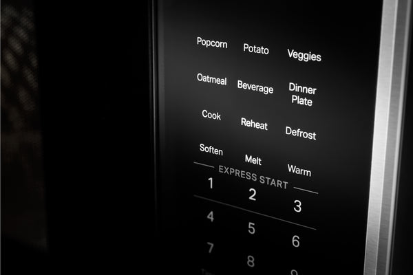 Primer plano del panel de control de un microondas con etiquetas de texto blancas para los alimentos y las opciones de cocción en una pantalla negra.