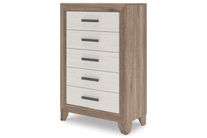 Un chest de 5 cajones con estructura en tono madera clara y frentes de cajón blancos, con tiradores horizontales en gris oscuro, presentado sobre un fondo blanco uniforme.