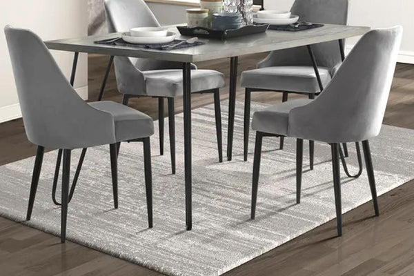 Mesa rectangular con patas acabadas en negro, tope de madera marrón, y cuatro sillas de color gris con respaldar en una sala moderna. 