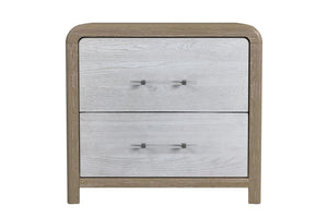 Mesa de noche con acabado en tono roble claro y frentes de gavetas en gris claro con textura de vetas. Incluye dos gavetas con manijas transparentes horizontales. Diseñado con bordes redondeados en color crema sobre un fondo blanco. 