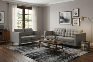 Sala moderna con sofá y loveseat grises de estilo contemporáneo, mesa de centro de madera, alfombra estampada y decoración minimalista. El espacio incluye lámpara de pie, arte de pared y ventana con luz natural.