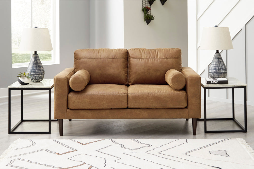 Loveseat de cuero marrón sobre un fondo blanco. 