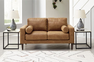 Loveseat de color marrón con dos mesas de esquina en una sala moderna. 