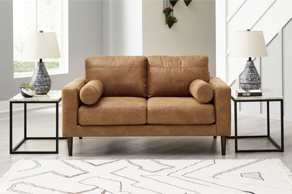 Loveseat de color marrón con dos mesas de esquina en una sala moderna. 