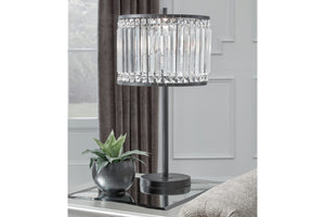 Lámpara de mesa decorativa con pantalla de cristal sobre superficie en ambiente de habitación.