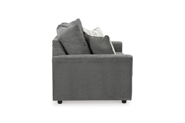 Vista lateral de loveseat gris con cojines decorativos sobre fondo blanco.